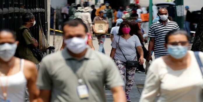People wearing protective masks walk on a street during a nationwide quarantine as the spread of the coronavirus disease (COVID-19) continues, in Caracas 1.050 nuevos casos